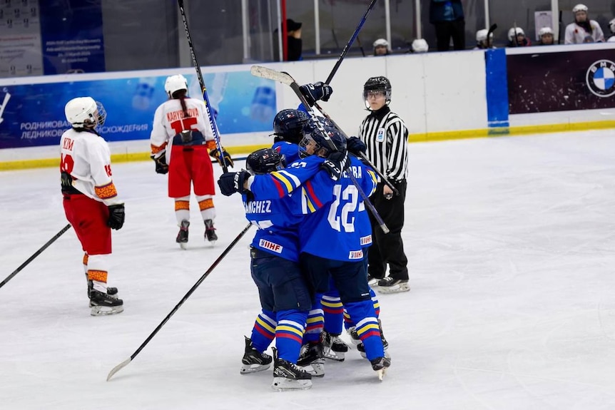 Members of the Philippines women's ice hockey team celebrate together on the ice after scoring a goal.