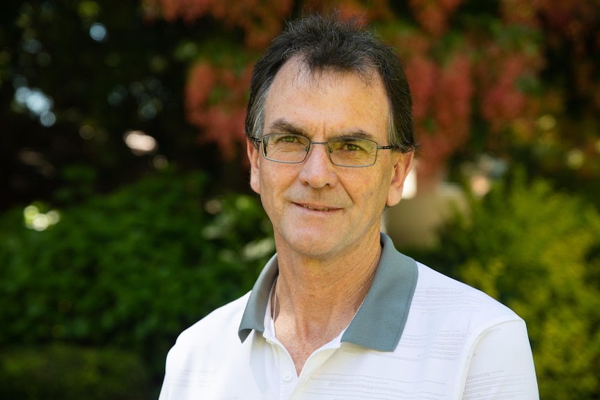 A man wearing glasses and a polo shirt smiling at the camera.