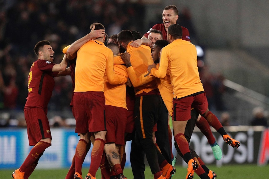Roma players jump on top of each other to celebrate a win