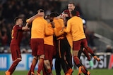Roma players jump on top of each other to celebrate a win