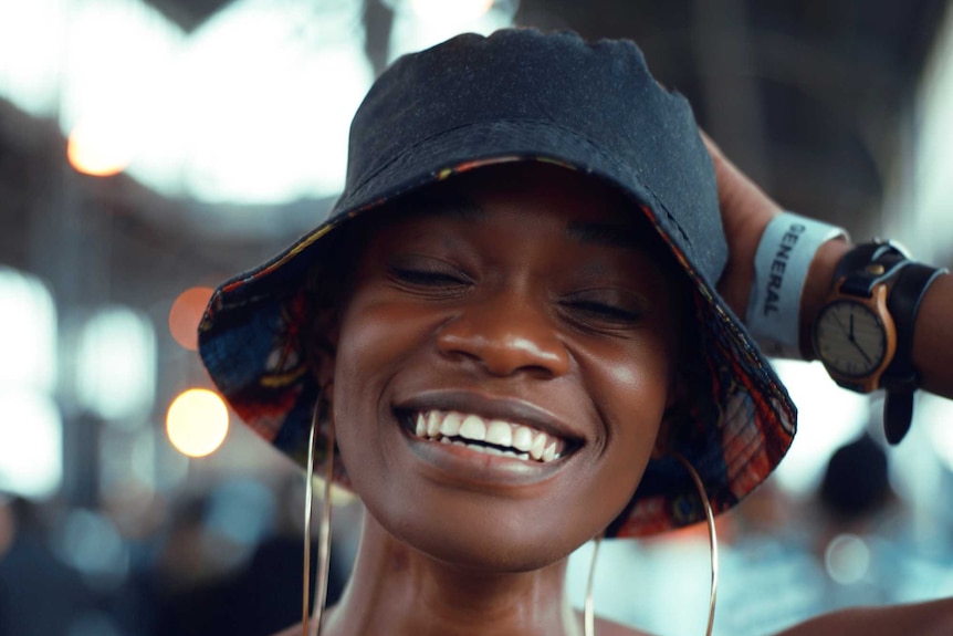 Woman with short hair wears a bucket hat and smiles