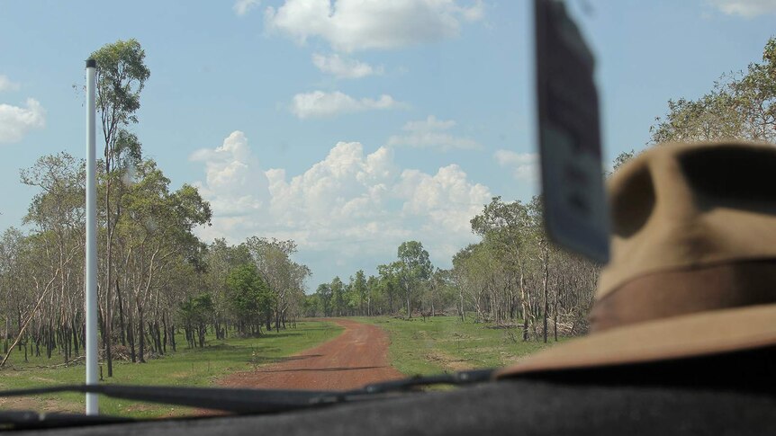 A photo of a dirt road in a remote pastoral station, viewed through a car's windshield.