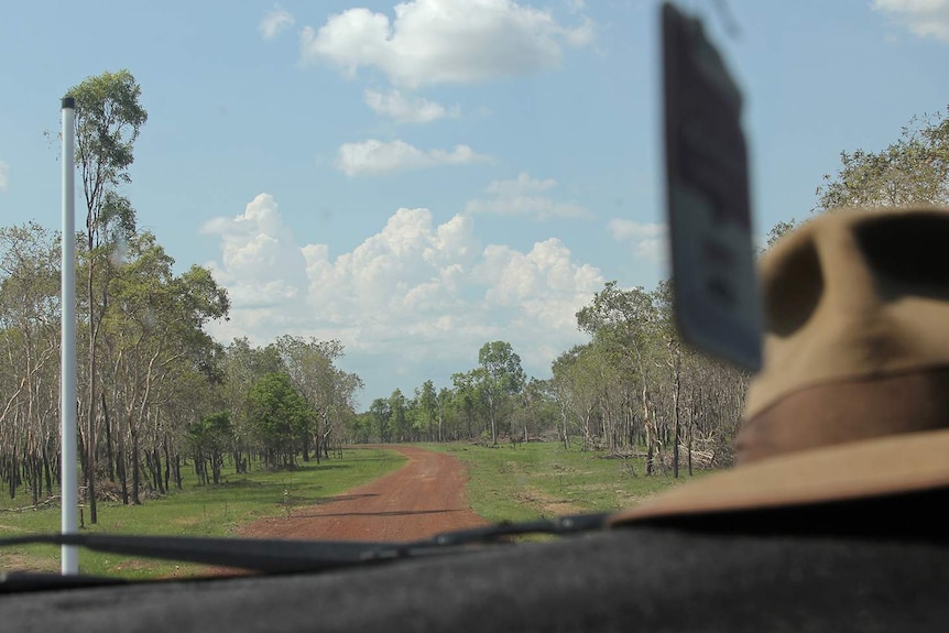 A photo of a dirt road in a remote pastoral station, viewed through a car's windshield.