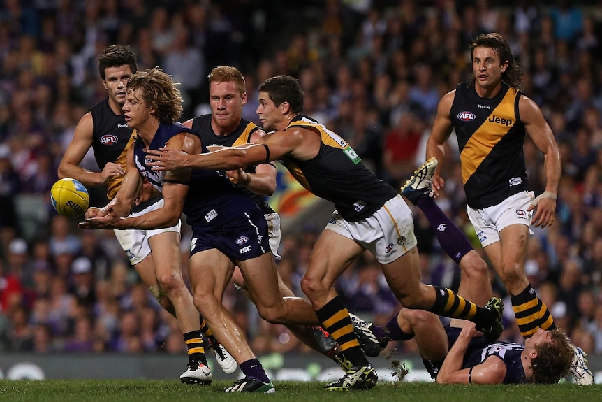 The Dockers' Nathan Fyfe handballs under pressure from the Tigers at Subiaco Oval.