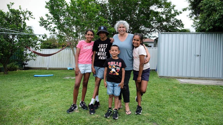 Jill Green smiling a family portrait with four young grandchildren.