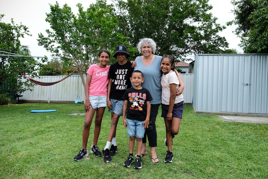 Jill Green smiling a family portrait with four young grandchildren.