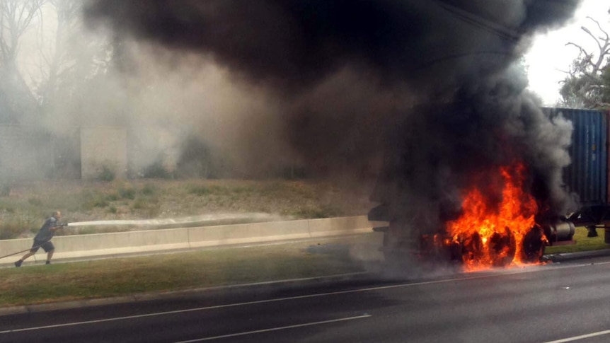 A man hoses down a burning container truck