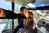 Courtney Courier and Cameron McDougall take a selfie while kissing on a ferris wheel.