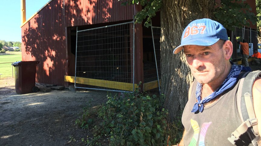 Homeless man michael stands in front of old grandstand that is being fenced off