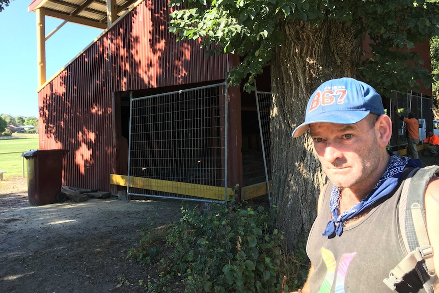 Homeless man michael stands in front of old grandstand that is being fenced off
