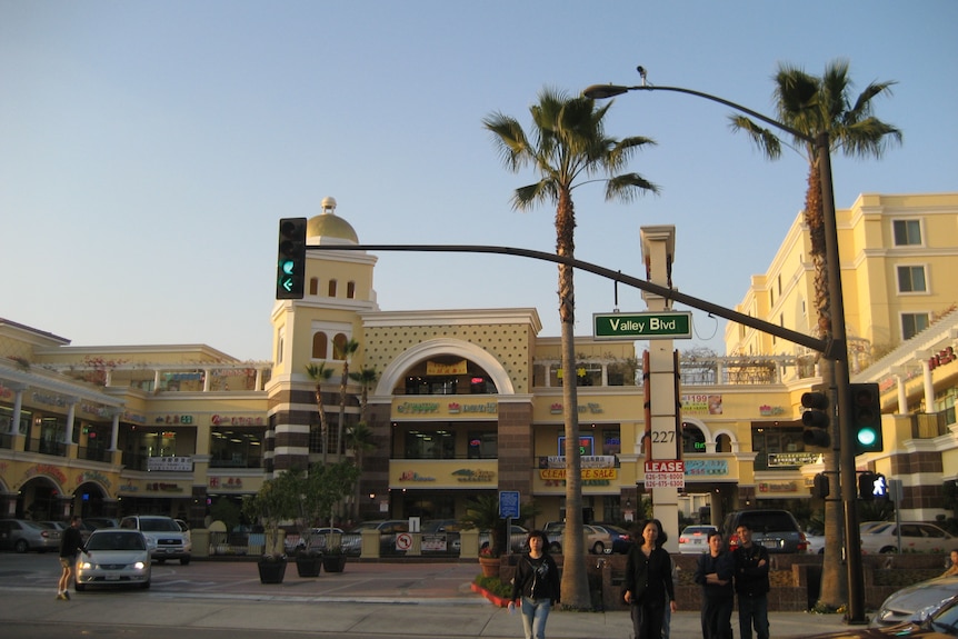 A photo of an oriental looking building behind palm trees and traffic lights in San Gabriel, USA.