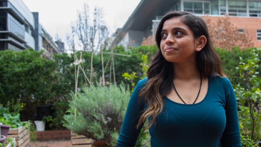Colour photograph of Hindu student Hemangini Patel standing in front of a rooftop garden.