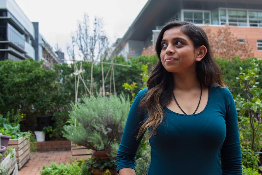 Colour photograph of Hindu student Hemangini Patel standing in front of a rooftop garden.