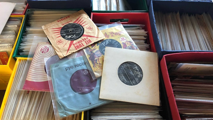 Records are stacked on boxes which are full of other albums.