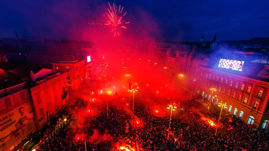 Fans light flares in the main square in Zagreb with fireworks going off.