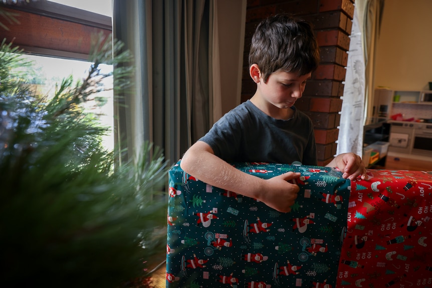 El hijo menor de Kate Nichol llama a la puerta de un regalo de Navidad envuelto antes del día de Navidad