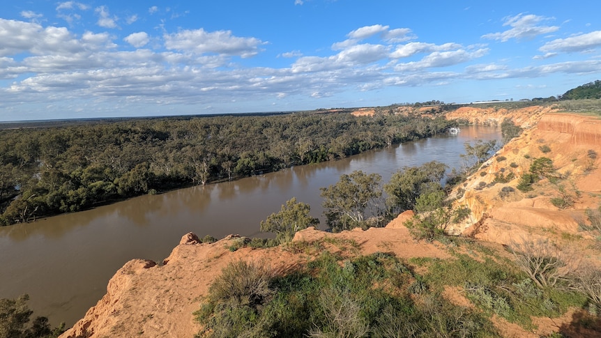 Limestone cliffs overlooking a river beneath a sunny sky.