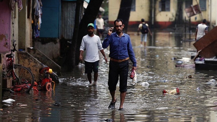 Men walk through floodwaters in Mumbai.