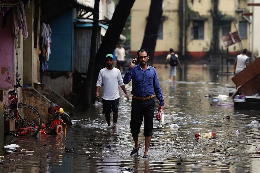Men walk through floodwaters in Mumbai.