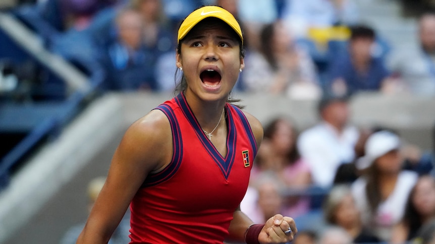 A visor-wearing female tennis player roars in triumph after winning a US Open title.