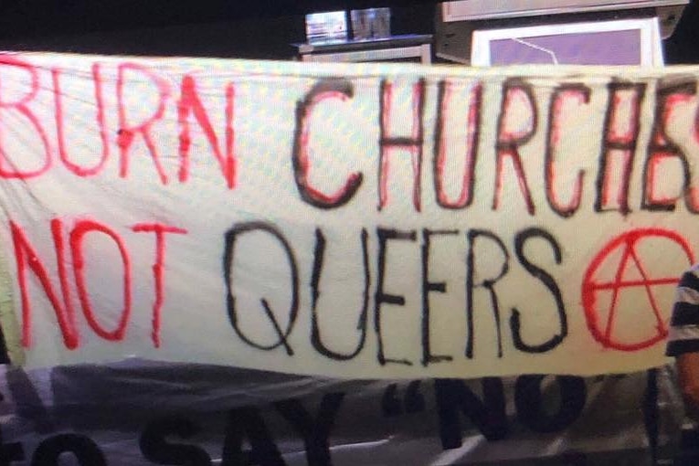 Protesters hold up a banner reading 'burn churches not queers'