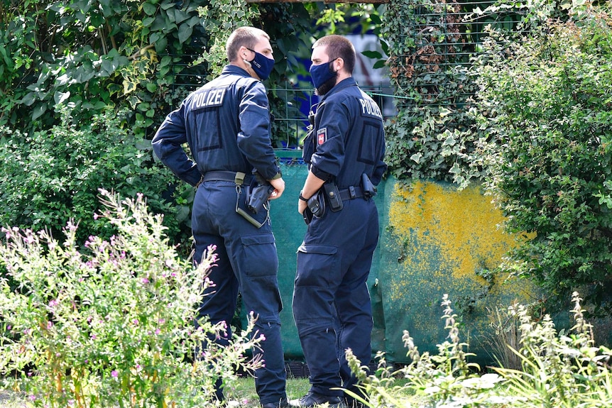 Two policemen in face masks stand in a garden