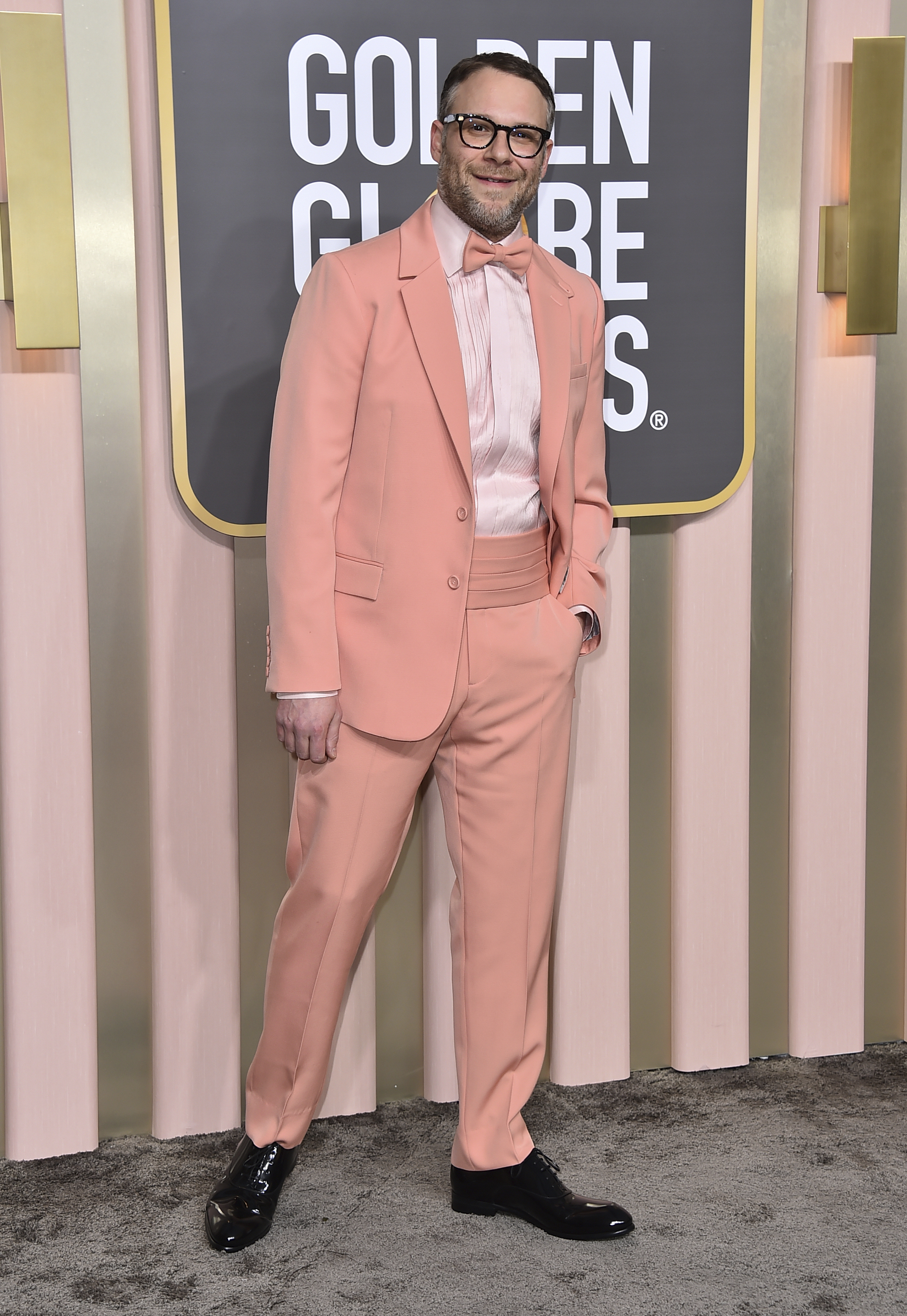 Seth Rogen wearing a peach coloured suit and bow tie with a pale pink shirt underneath. 