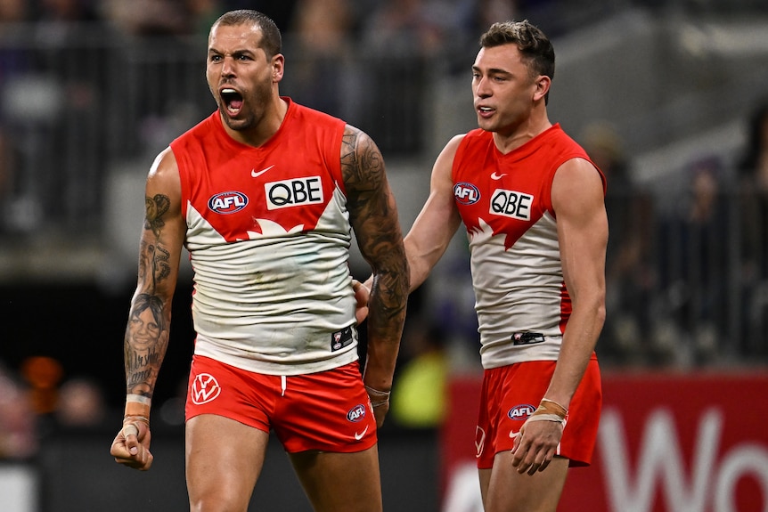Two Sydney Swans AFL players celebrate a goal.