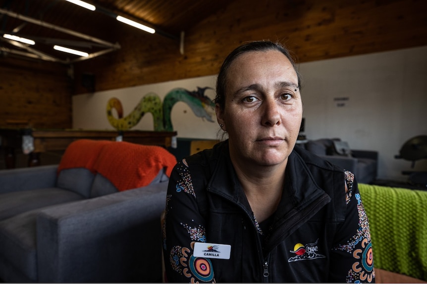 A woman is sitting on a sofa and looking at the camera