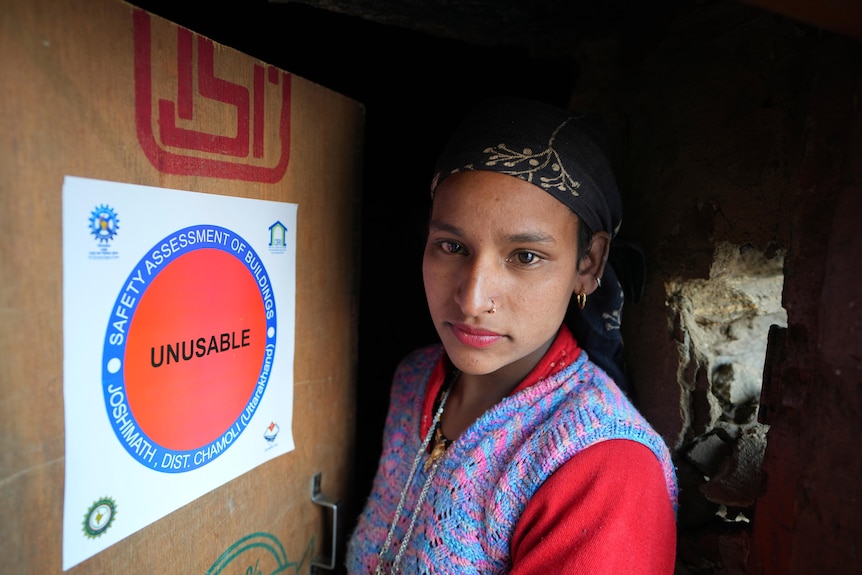 A woman stands next to a red sign which says "unsuitable"