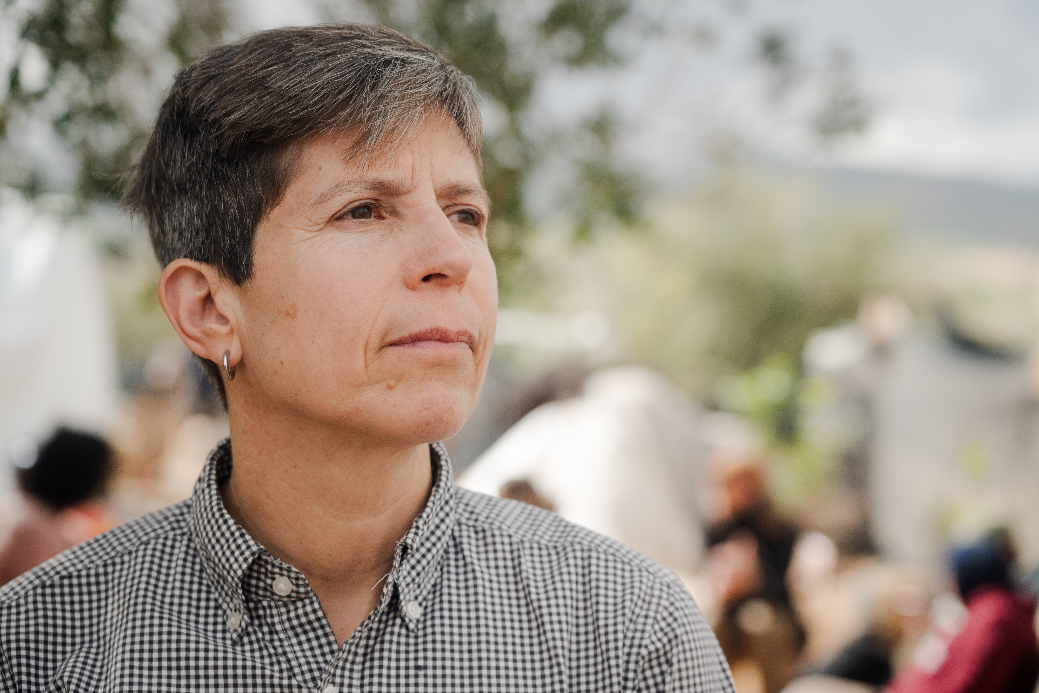 A close up of a grey-haired person wearing a chequered, long sleeve shirt.