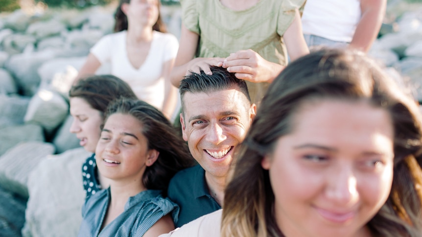 Parenting expert Justin Coulson surrounded by his 6 daughters