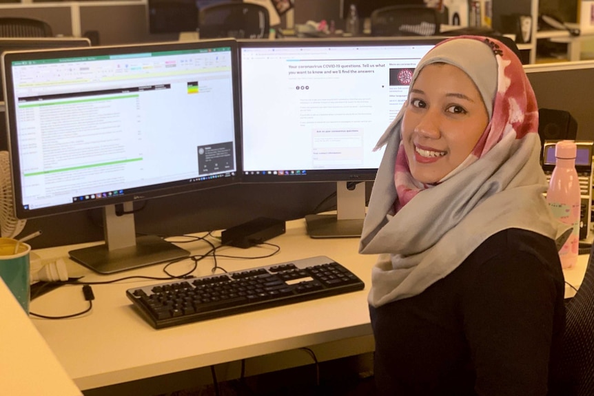 Womanl in a headscarf sitting in front of a computer