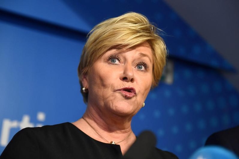 Siv Jensen a woman speaking at a conference in front of a blue background.