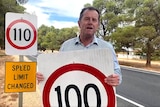Tim Whetstone holds a speed limit sign.