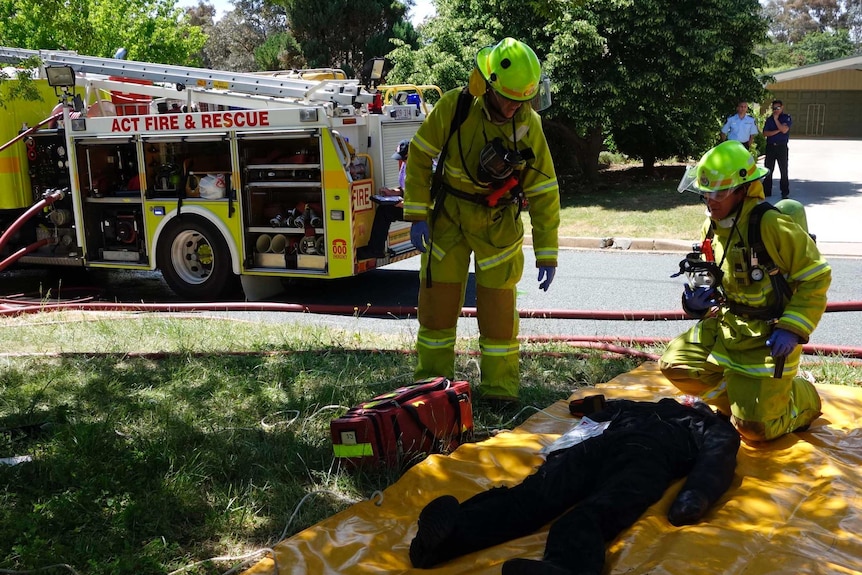 Firefighters respond to a dummy casualty who was pulled from the burning house during the exercise.