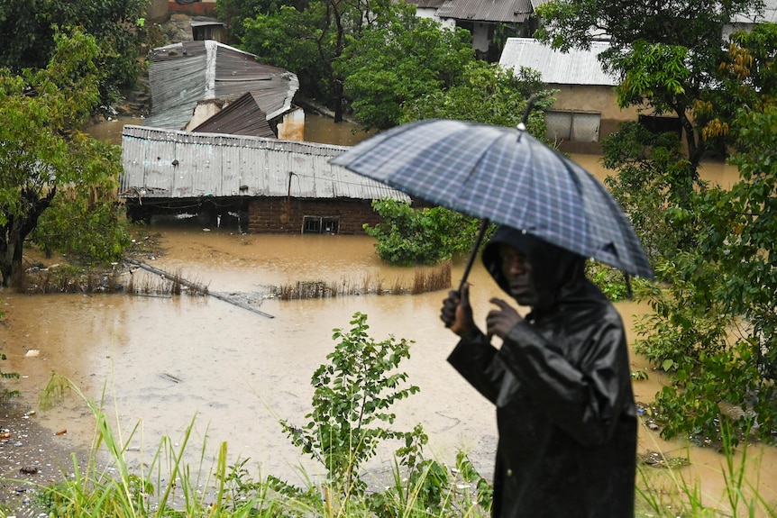A man passes houses that are submerged in flood waters in Blantyre, Malawi.