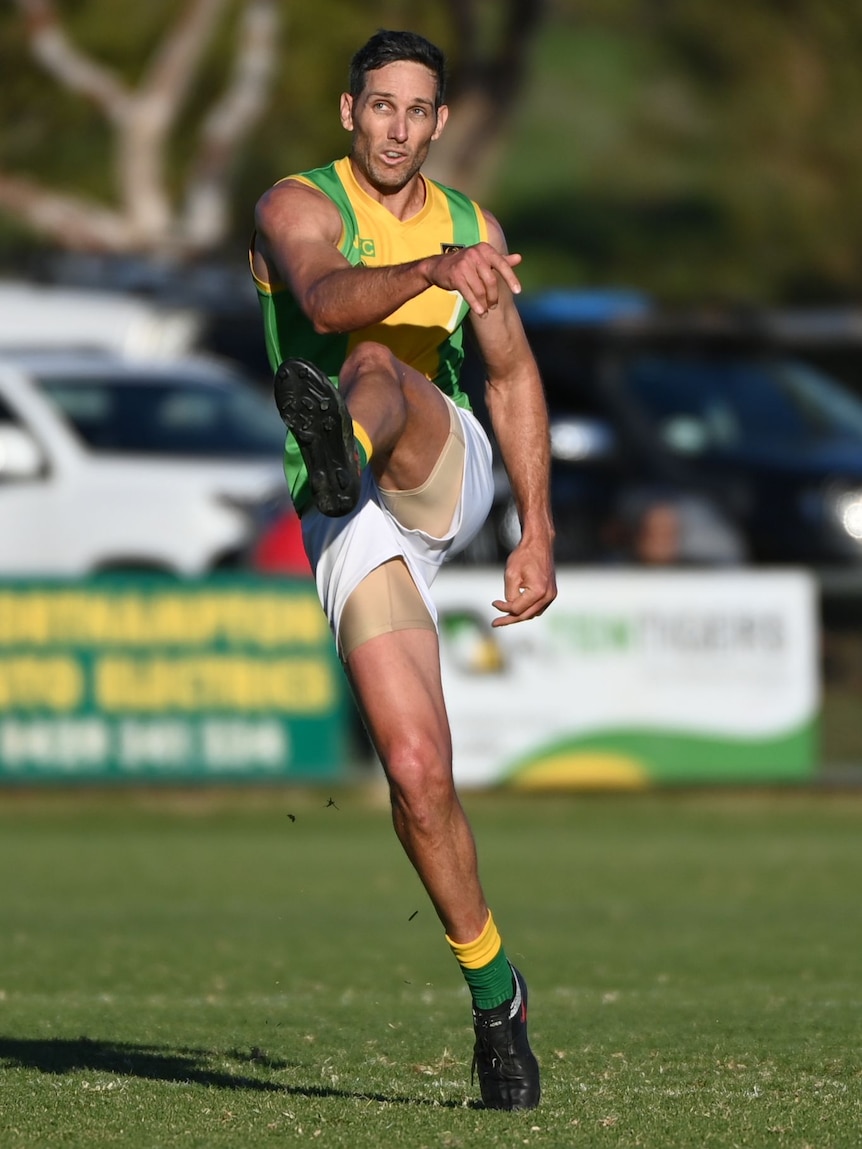 Man in football uniform with one leg in the air after kicking a football