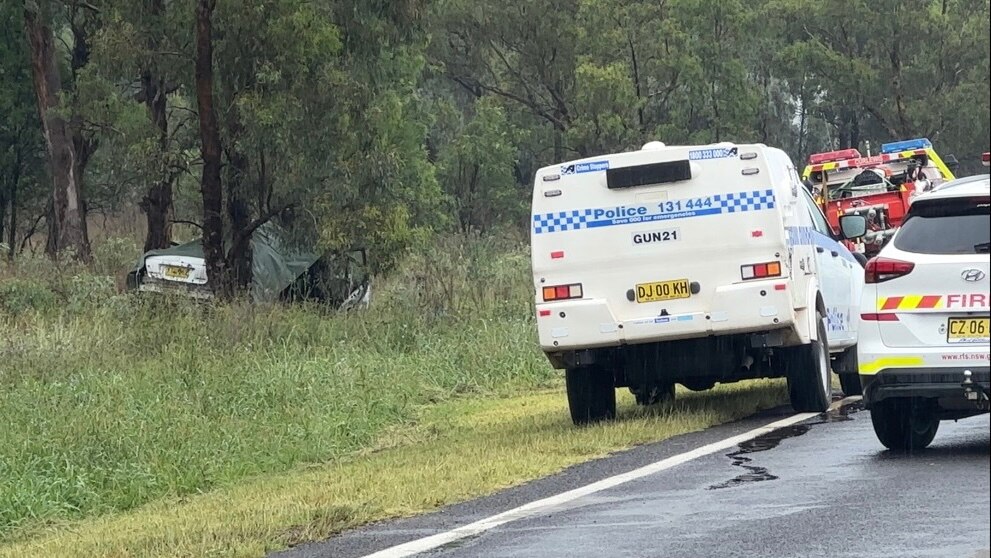 A crashed car sits on the side of the road covered in a tarp with police rescue surrounding 