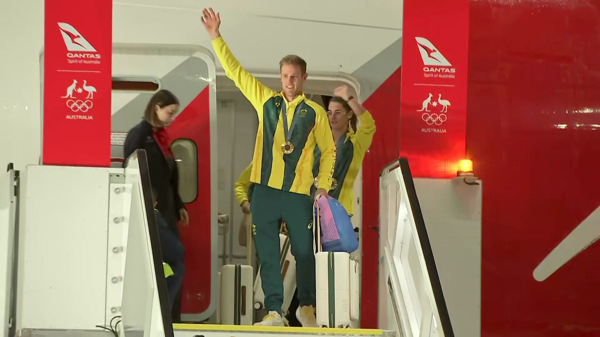 Matt Wearn, who won back-to-back gold in the sailing, waving and wearing medal getting off plane from Paris