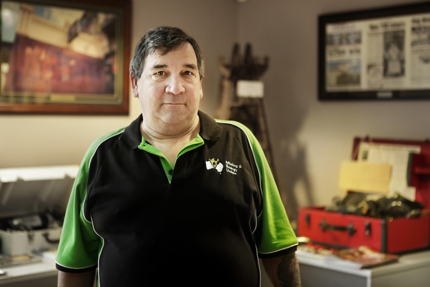 a man in an MEU t shirt poses in an office