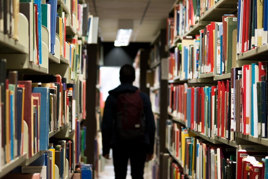 Unidentified student in a library aisle.