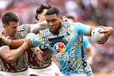 Gold Coast NRL player Moeaki Fotuaika with ball in hand, fending a defender in the other hand.