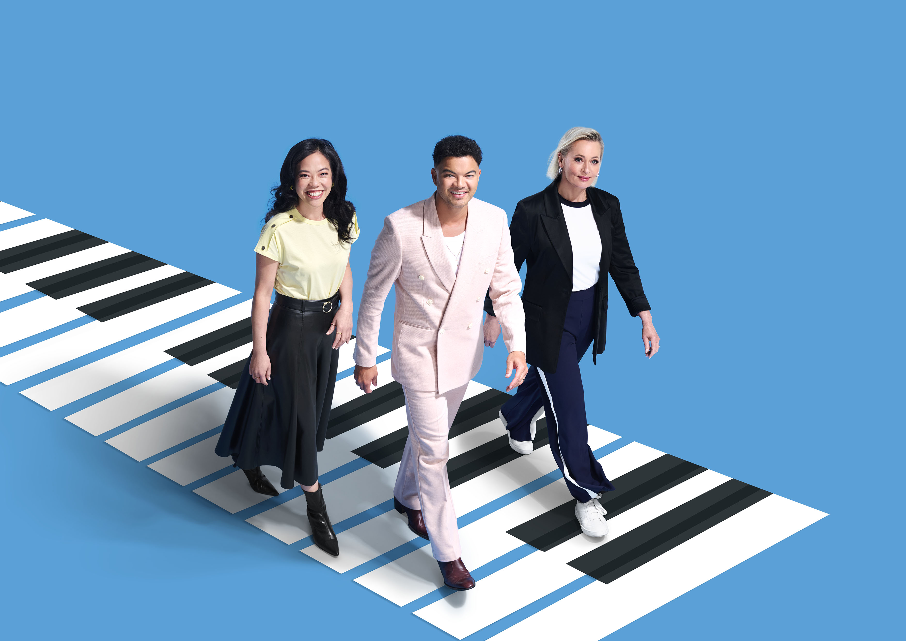 Andrea Lam, Guy Sebastian and Amanda Keller stride across a graphic piano keyboard on a blue background.