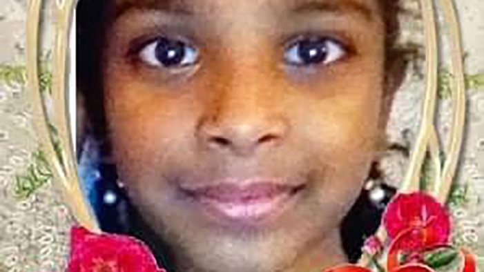 A head shot of a smiling young girl in a frame with red flowers around it.