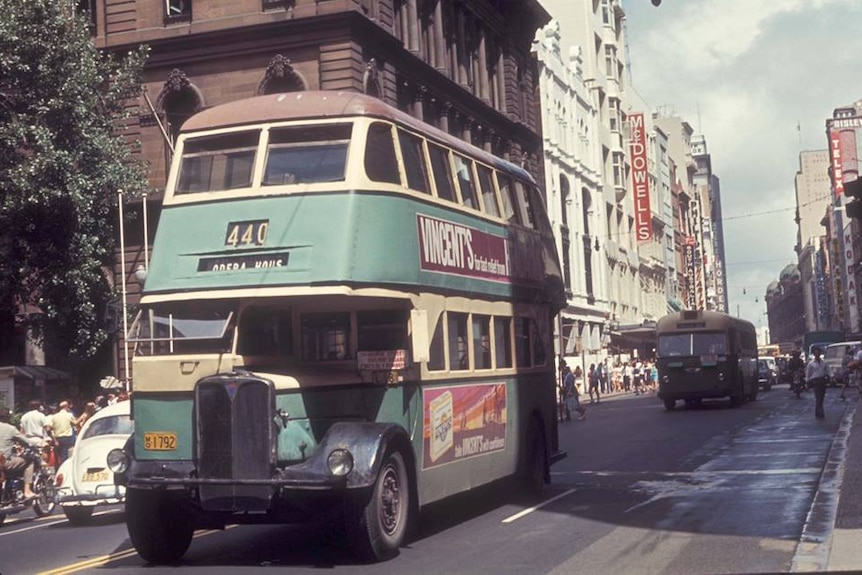 A colour photo of a bus traveling down George Street at Martin Place in February 1971.