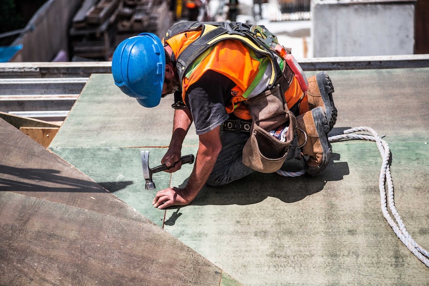 A builder with a hammer on a deck.