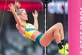 Nina Kennedy of Australia celebrates going clear in the pole vault by raising her arms while suspended in the air