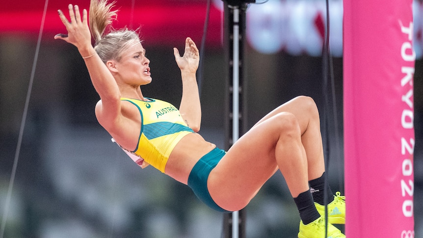 Nina Kennedy of Australia celebrates going clear in the pole vault by raising her arms while suspended in the air