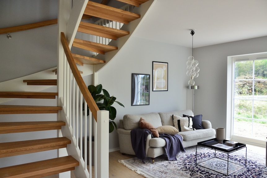 A photo of a living room with wooden stairs in the foreground. 